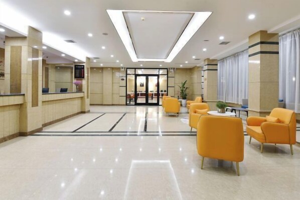 Una hall d'albergo con reception, area relax e un'ampia porta d'ingresso in vetro.