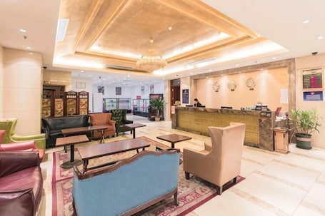 A hotel lobby with a reception desk, seating area, and a chandelier.. Beijing Ruya Business Hotel (Wangjing Subway Station)