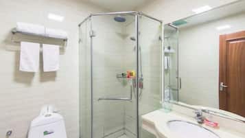 Un baño con cabina de ducha de vidrio, un lavabo con espejo y un perchero con toallas.