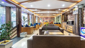 A modern interior with wooden beams, seating areas, and a reception desk. - Hotel Airport Deepshree (Kathmandu)