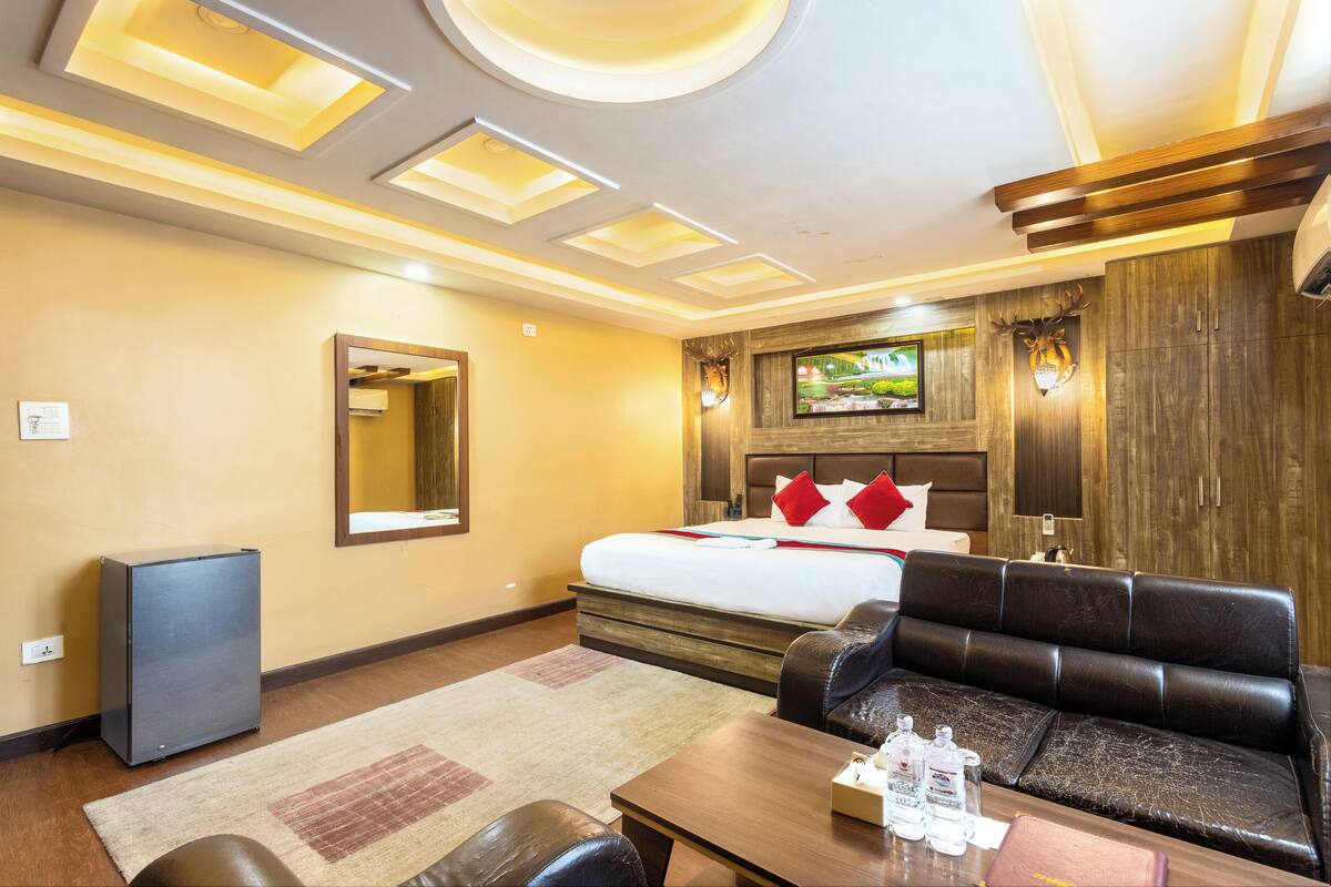 A hotel room with a bed, a sofa, a coffee table, a TV, and a wardrobe.