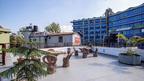 A rooftop terrace with potted plants, wooden tables, and a sign for Hotel Airport Deepeshree. - Hotel Airport Deepshree (Kathmandu)