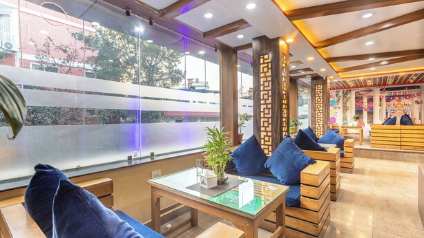 A modern hotel lobby with wooden furniture, a glass table, and a view of the city through large windows. - Hotel Airport Deepshree (Kathmandu)
