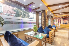 A modern hotel lobby with wooden furniture, a glass table, and a view of the city through large windows. - Hotel Airport Deepshree (Kathmandu)
