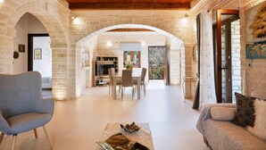 A spacious living area with a stone wall, wooden ceiling, and a dining area with a table and chairs. - Peacefull Stone-Built Villa (Mylopotamos)