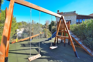 Relax in a charming outdoor space with a wooden swing set and slide.