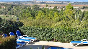 A pool area with lounge chairs, a hedge, and a view of a town and mountains in the distance. - Finca Can Xisco Domatiga 250 Stone villa with swimming pool and high speed internet access (Ariany)