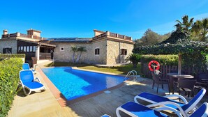 A pool area with lounge chairs, a stone building, and a wooden deck. - Finca Can Xisco Domatiga 250 Stone villa with swimming pool and high speed internet access (Ariany)