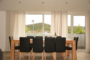 Enjoy meals in this dining area with a wooden table and six chairs, surrounded by large windows offering a view of the surrounding landscape.
