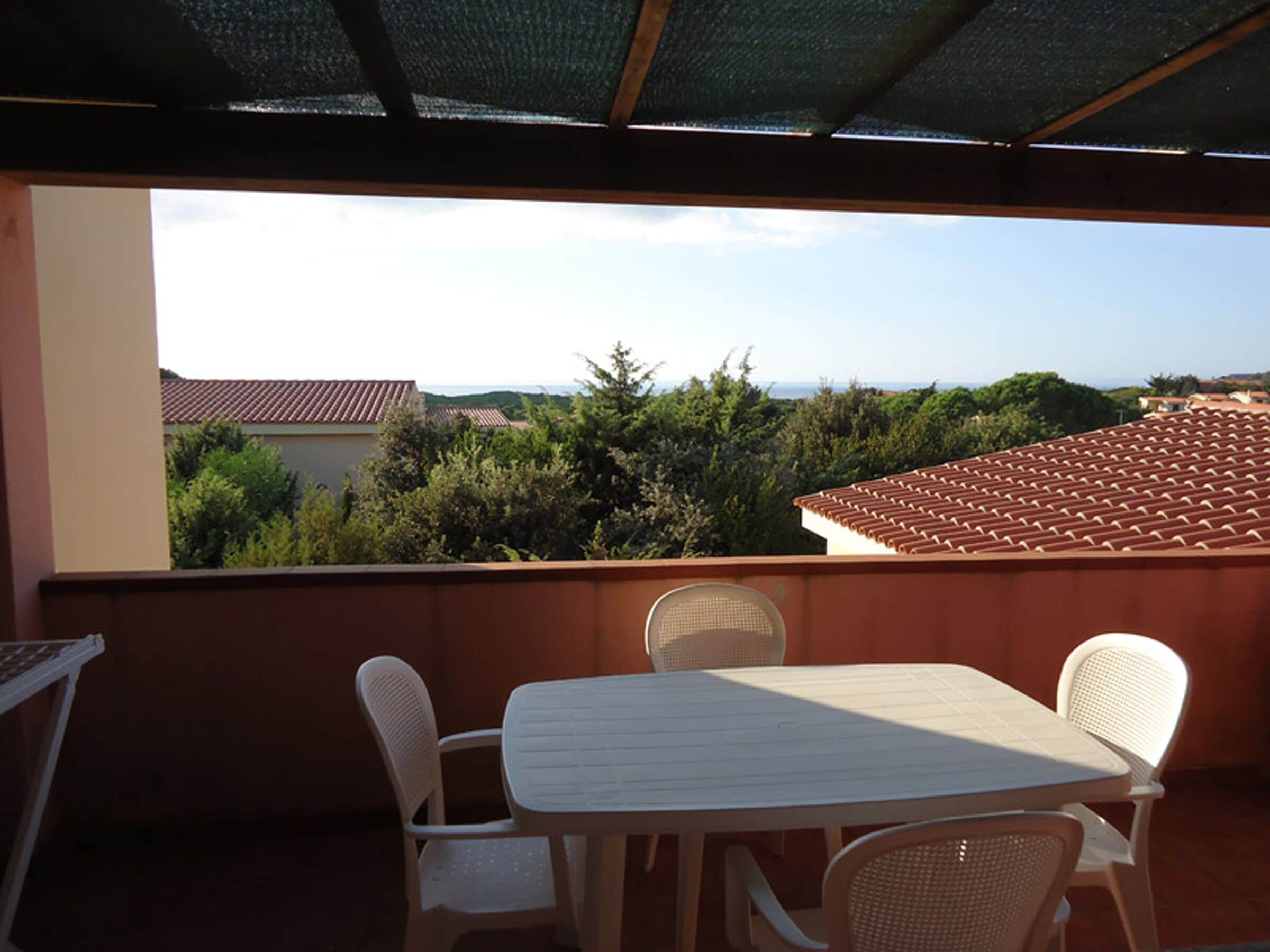Ein Balkon mit Tisch und Stühlen, mit Blick auf eine Wohngegend mit Häusern und Bäumen.