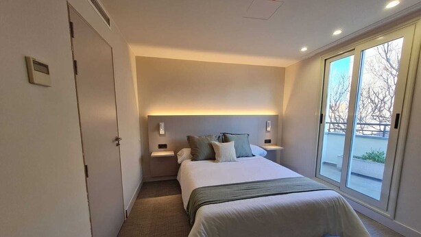 Een moderne hotelkamer met een groot bed, een nachtkastje, een raam met uitzicht en een deur.