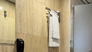 Een moderne badkamer met een houten wand, toilet, wastafel, handdoekhouder en een handdroger.