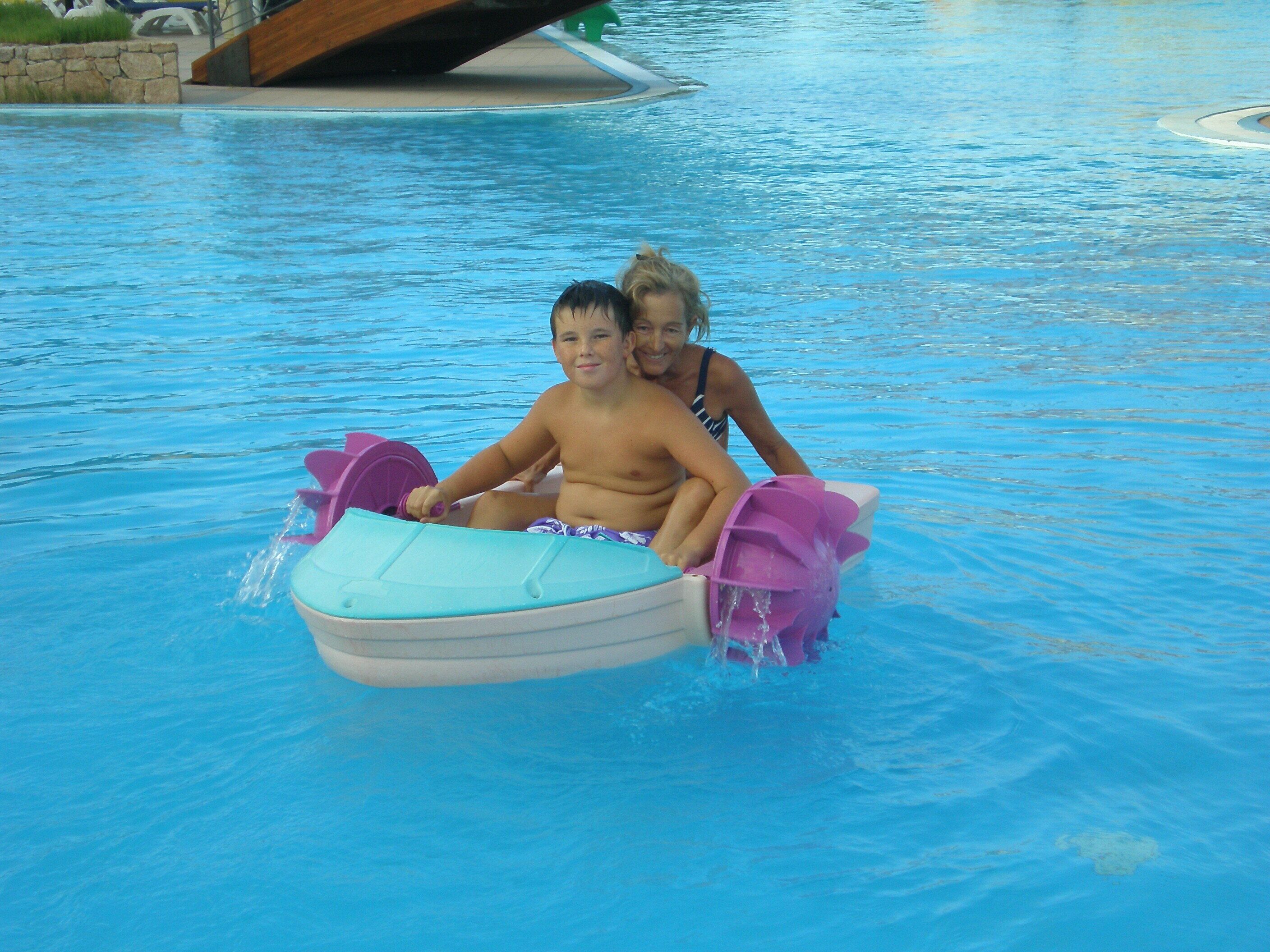A pool with a child on a small inflatable boat.