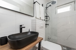 A modern bathroom with a black vessel sink, a wooden countertop, a white toilet, and a glass shower enclosure. - Luxury Villa Solis (Karlobag)