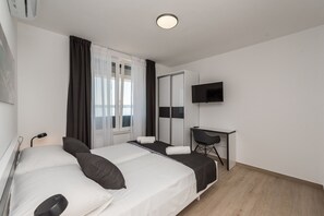 A modern hotel room with a bed, a desk, a TV, and a large window with curtains. - Luxury Villa Solis (Karlobag)