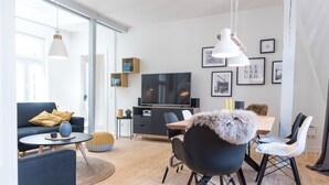 A modern living room with a sofa, dining table, chairs, and a TV. - fewo1846 - flensBURG / centrally located, elegant maisonette apartment on the 4t (Flensburg)
