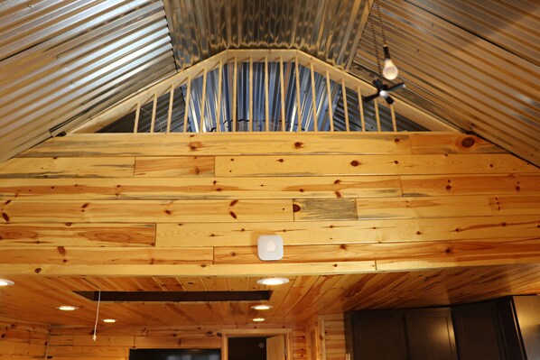 A wooden interior with a sloped ceiling, wooden walls, and a ceiling fan.