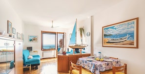 Ein helles Zimmer mit einem Esstisch, Stühlen, einem kleinen Modellboot und einem Gemälde eines Bootes an der Wand.