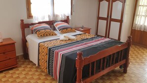 Une chambre à coucher bien rangée, avec un lit en bois, une table de chevet avec une lampe et une petite commode.