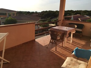Ein Balkon mit Tisch, Stühlen, einer Couch und Blick auf die Umgebung.