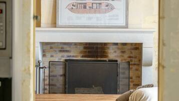 A living room with a fireplace, a framed architectural drawing above it, and a sofa.