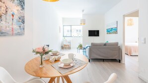 Ein modernes Wohnzimmer mit einer Couch, einem Esstisch mit Schüsseln und Tassen sowie einem Bild an der Wand.