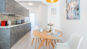 Eine moderne Küche mit grauen Schränken, einem Holztisch und weißen Stühlen.