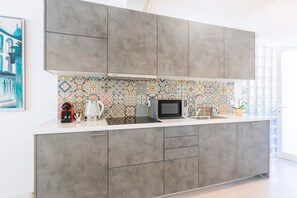 A modern kitchen with grey cabinets, a patterned backsplash, and a microwave on the counter.