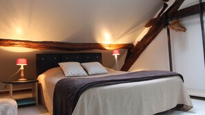 A bedroom with a bed, two bedside tables, a lamp, and exposed wooden beams. - Character property (CHARBONNIERES LES VIEILLES)