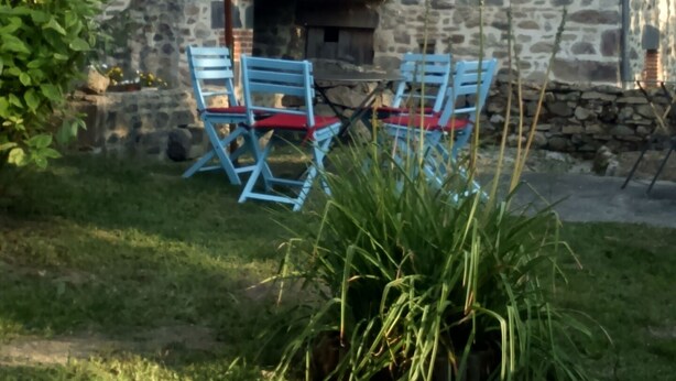 A stone building with a small balcony and a table with blue chairs under a white umbrella. - Character property (CHARBONNIERES LES VIEILLES)