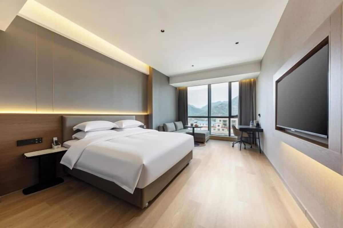 Une chambre d’hôtel moderne dotée d’un grand lit, d’un bureau et d’une grande fenêtre donnant sur la ville.
