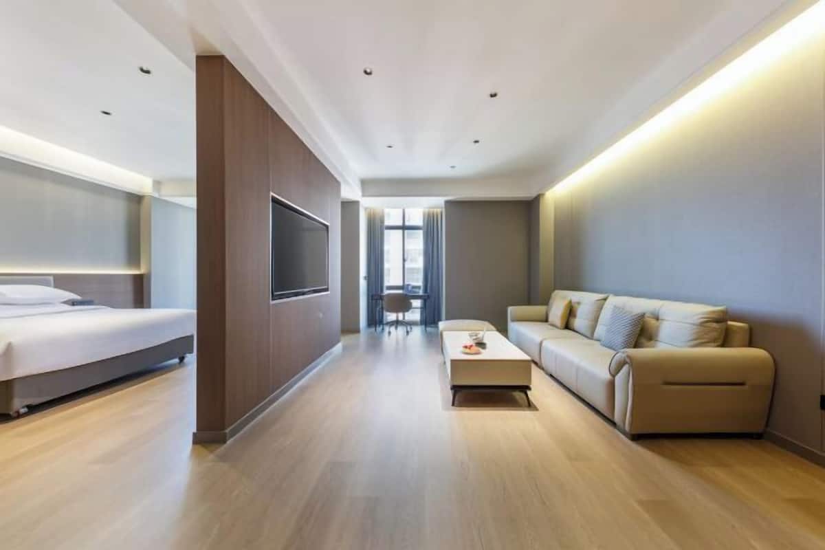 Une chambre d’hôtel moderne équipée d’un lit, d’un canapé, d’une télévision et d’une table à manger.