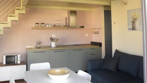 A modern kitchen with a central island, a dining area with a white table and chairs, and a staircase leading to an upper level. - Only 20 min from Olbia: charming 2-bedroom apartment in San Pantaleo with wifi (San Pantaleo)