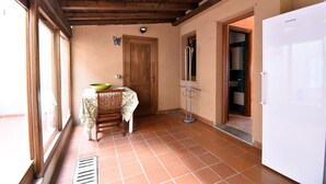 A kitchen with a wooden ceiling, a white refrigerator, a wooden door, and a window.