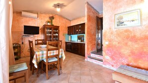 A dining area with a table set for four, a television, and a kitchen in the background.