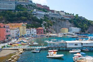 Une ville côtière dotée d’un port de plaisance, de bâtiments aux couleurs vives et d’une colline rocheuse.