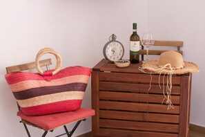 Ein Holztisch mit einem gewebten Hut, einer Weinflasche, einem Weinglas und einer Uhr.