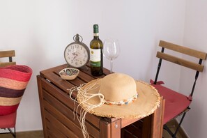 Een houten tafel met een geweven hoed, een wijnfles, een glas en een klok.