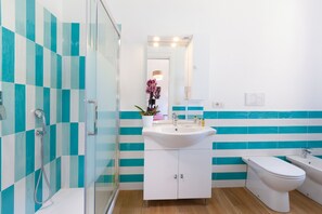 Un baño moderno con cabina de ducha de vidrio, un lavabo blanco, un inodoro y una bañera.