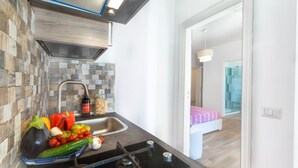 Una cocina con diseño moderno, que incluye un fregadero, estufa y una variedad de verduras frescas sobre la encimera.