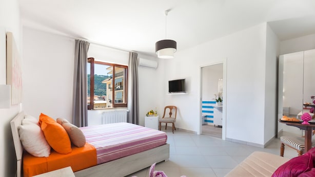 Une chambre moderne avec un lit, un canapé, une télévision et une vue sur l’extérieur.
