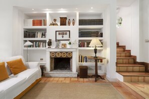 Un salon avec une cheminée, des étagÚres à livres, un canapé et un escalier.