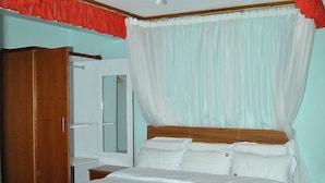 Ein Schlafzimmer mit einem Bett, einem Kleiderschrank, einem Spiegel und einem roten und weißen Vorhang.