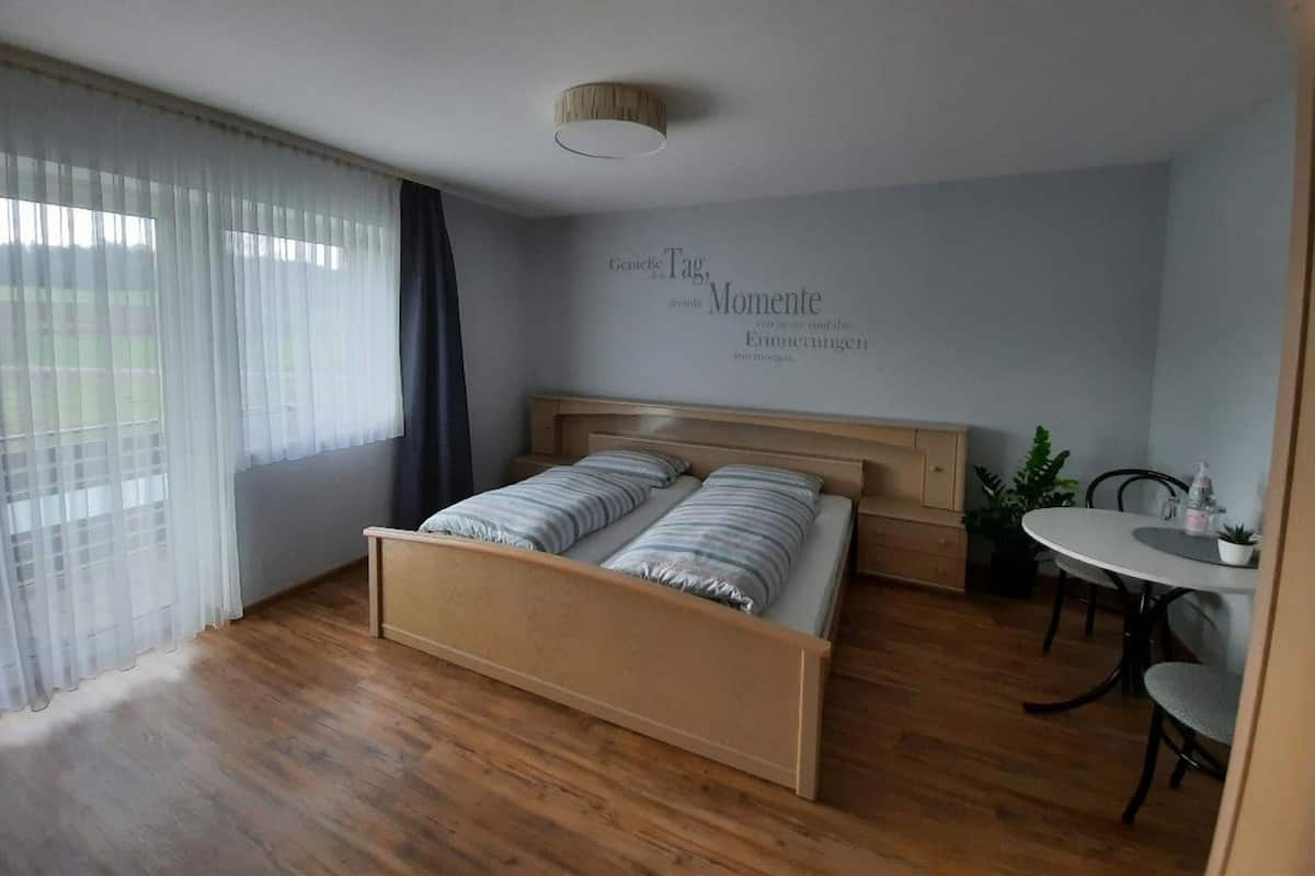 A bedroom with a wooden bed, a small table, and a chair.