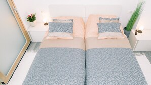 A double bed with matching pillows and a patterned bedspread. There are bedside tables with lamps and a potted plant. - Wellness Paradise Apartment (Bled)