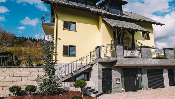 A two-story building with a yellow facade, a balcony, and a staircase leading to the entrance. - Wellness Paradise Apartment (Bled)