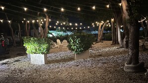 An outdoor area with string lights, trees, and seating arrangements. - Luxury cottage in the heart of paradise (Key Largo)