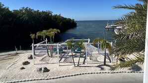 A beachside area with a dock, lounge chairs, and palm trees. - Luxury cottage in the heart of paradise (Key Largo)