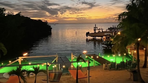 A beachside pool area with a view of the ocean at sunset. - Luxury cottage in the heart of paradise (Key Largo)
