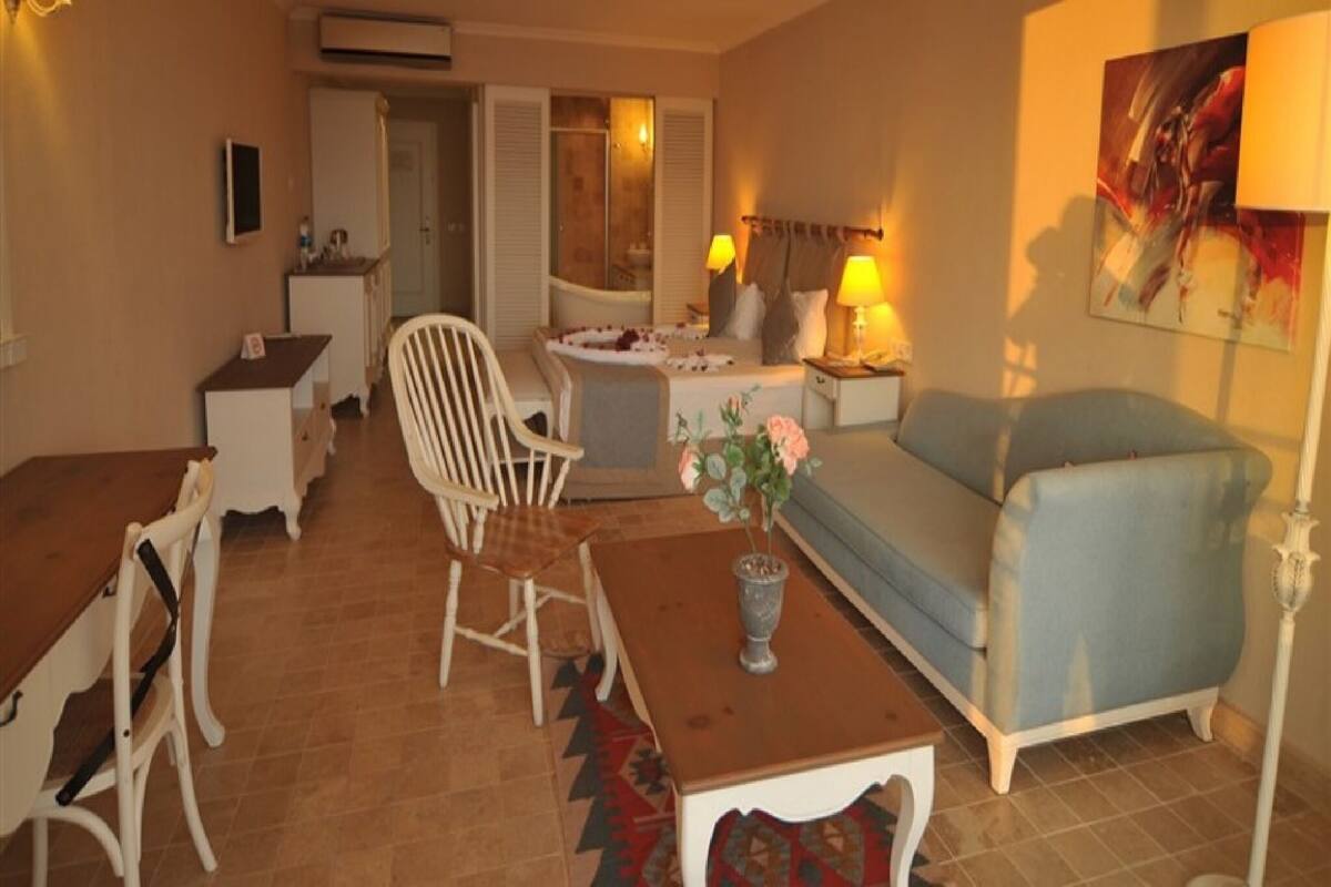 Un salon avec un canapé, un fauteuil, une petite table, une lampe et un tableau accroché au mur.